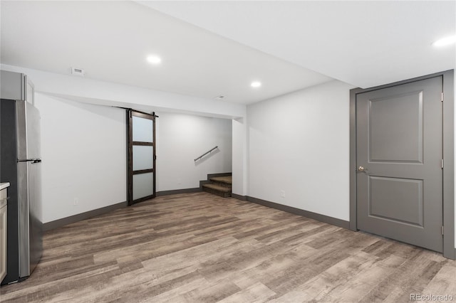 basement featuring stainless steel fridge and light hardwood / wood-style floors