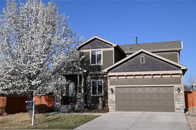 craftsman-style home with concrete driveway, stone siding, fence, and an attached garage