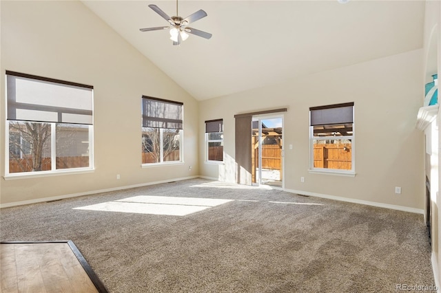 empty room with a healthy amount of sunlight, high vaulted ceiling, ceiling fan, and carpet flooring