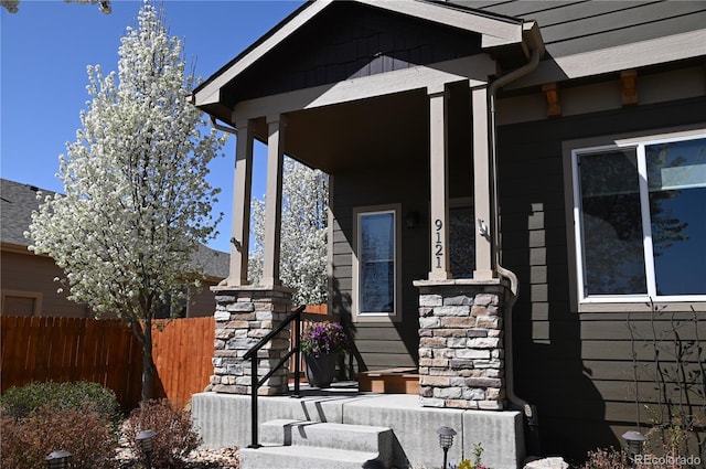 property entrance featuring stone siding and fence