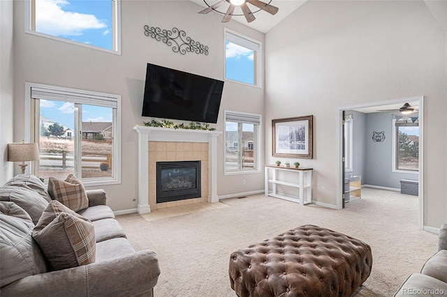 carpeted living room featuring high vaulted ceiling, ceiling fan, baseboards, and a tile fireplace