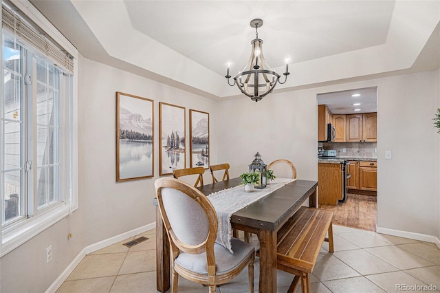 dining area with plenty of natural light, light tile patterned floors, visible vents, and a tray ceiling