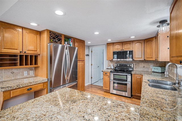 kitchen featuring tasteful backsplash, light wood-style flooring, appliances with stainless steel finishes, open shelves, and a sink