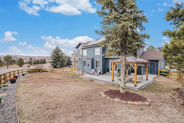 back of house with a gazebo, a fenced backyard, a gate, and roof mounted solar panels