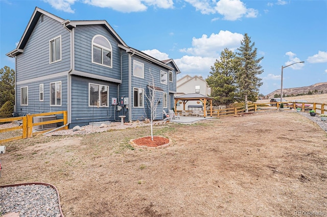 back of property with a patio area, a fenced backyard, and a gazebo