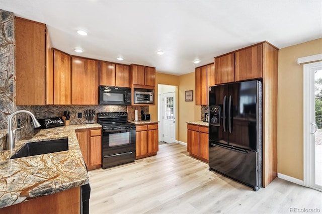 8460 Corona St, Denver, CO 80229 - kitchen featuring black appliances, brown cabinetry, tasteful backsplash, light wood-style floors, and recessed lighting