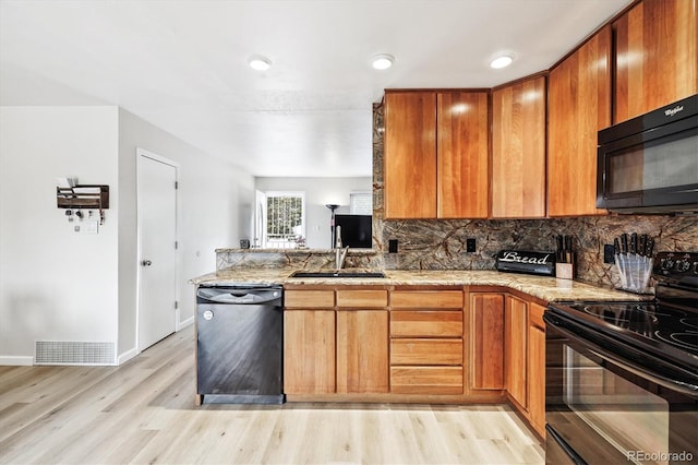 8460 Corona St, Denver, CO 80229 - kitchen featuring black appliances, light stone countertops, backsplash, light wood-style floors, and a peninsula