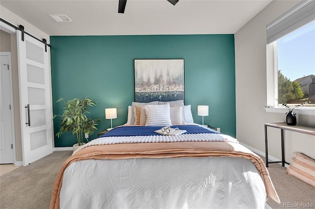 carpeted bedroom featuring a barn door and ceiling fan