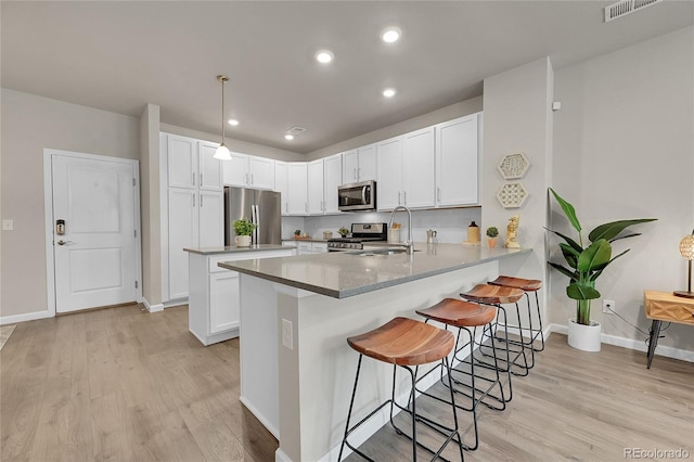 kitchen featuring sink, appliances with stainless steel finishes, kitchen peninsula, pendant lighting, and white cabinets