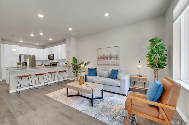 living room with recessed lighting, light wood-style flooring, and baseboards