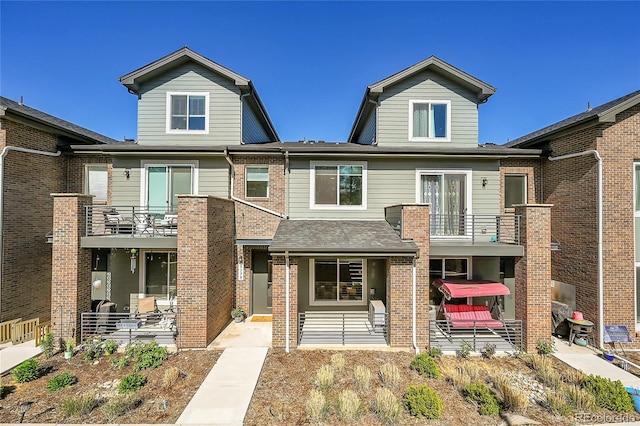 view of property with brick siding, a balcony, and a patio area