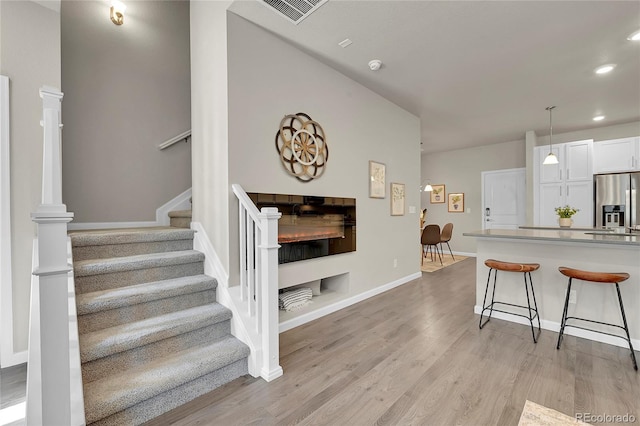 interior space with a fireplace, recessed lighting, wood finished floors, and visible vents