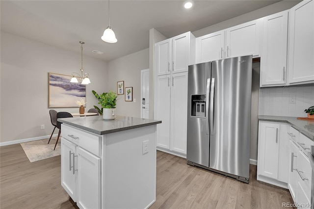 kitchen with stainless steel refrigerator with ice dispenser, a center island, light wood-type flooring, white cabinets, and decorative light fixtures