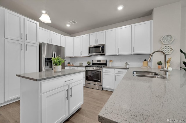kitchen featuring visible vents, light wood-type flooring, a sink, light stone counters, and stainless steel appliances