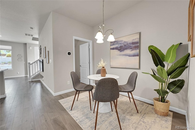 dining room with visible vents, dark wood-style floors, stairway, and an inviting chandelier