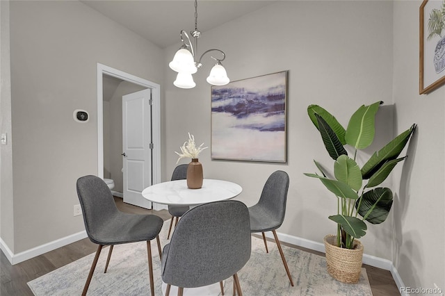 dining area featuring wood finished floors, baseboards, and a notable chandelier