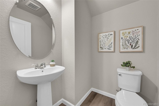 bathroom with visible vents, wood finished floors, a sink, baseboards, and toilet
