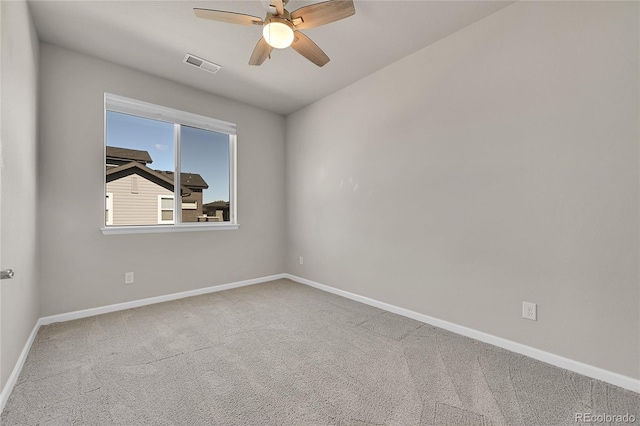 spare room with carpet floors, baseboards, a ceiling fan, and visible vents