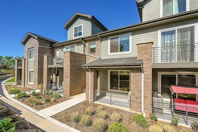view of property with brick siding and a balcony