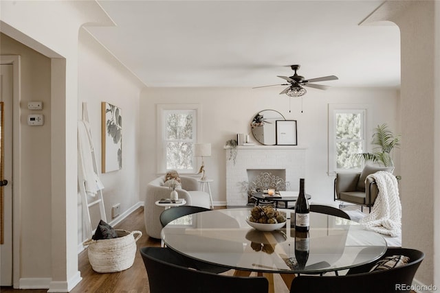 3055 Clermont St, Denver, CO 80207 - dining room featuring a ceiling fan, a fireplace, wood finished floors, and baseboards