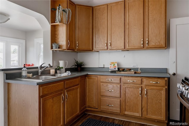 3055 Clermont St, Denver, CO 80207 - kitchen with a sink, stainless steel gas stove, dark wood-type flooring, a peninsula, and brown cabinetry
