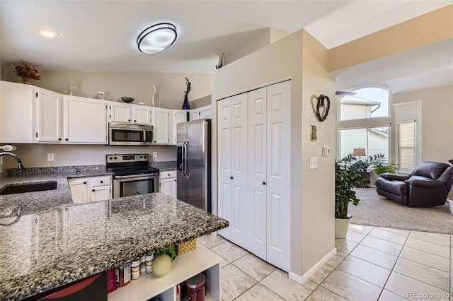 kitchen featuring light tile patterned flooring, sink, white cabinetry, dark stone countertops, and appliances with stainless steel finishes