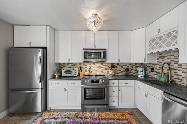 kitchen featuring appliances with stainless steel finishes, white cabinets, a sink, and decorative backsplash