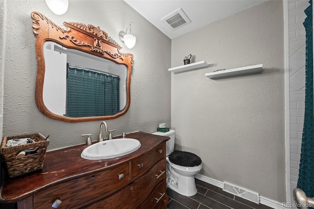 full bath with visible vents, a textured wall, vanity, and toilet