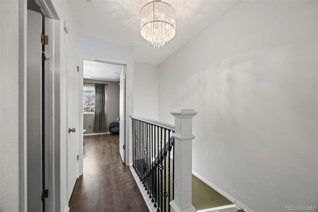 hall with a notable chandelier, baseboards, wood finished floors, and an upstairs landing