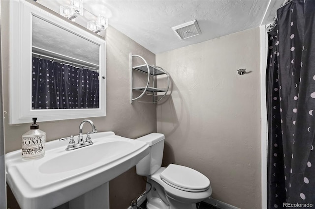 full bathroom featuring a textured wall, toilet, a sink, visible vents, and a shower with curtain