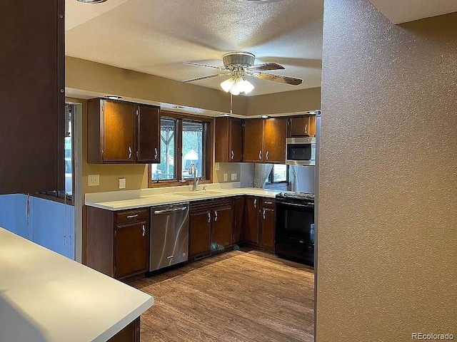 kitchen with appliances with stainless steel finishes, hardwood / wood-style floors, sink, ceiling fan, and dark brown cabinets