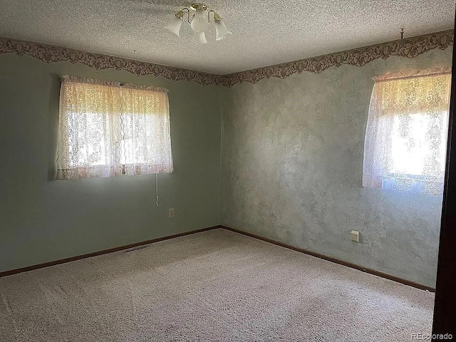 empty room featuring a healthy amount of sunlight, carpet, and a textured ceiling