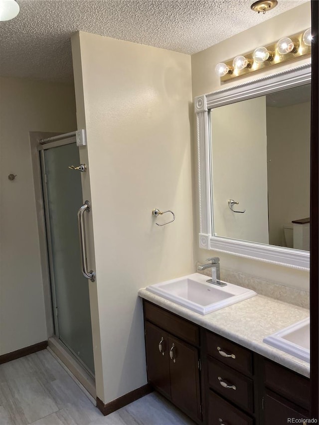 bathroom with vanity, a textured ceiling, and walk in shower