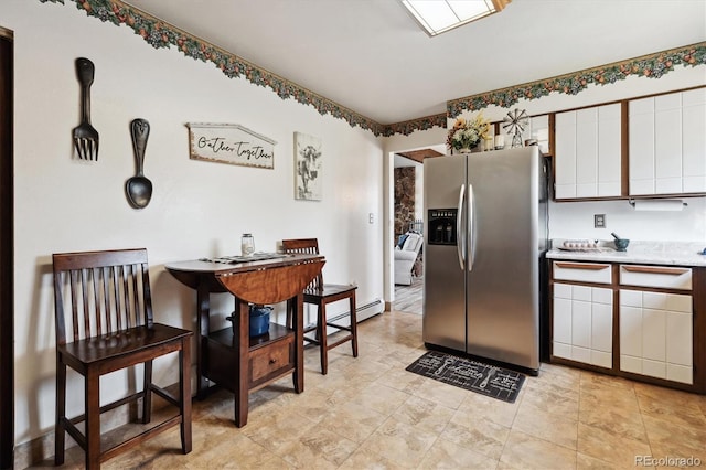 kitchen with white cabinets, a baseboard heating unit, stainless steel fridge, and light tile patterned floors