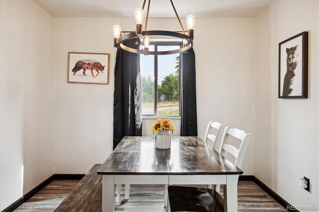 dining area featuring dark wood-type flooring and a chandelier