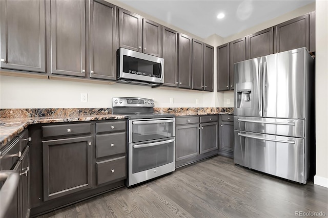11565 Crow Hill Dr, Parker, CO 80134 - kitchen with stainless steel appliances, wood finished floors, dark stone countertops, dark brown cabinets, and recessed lighting