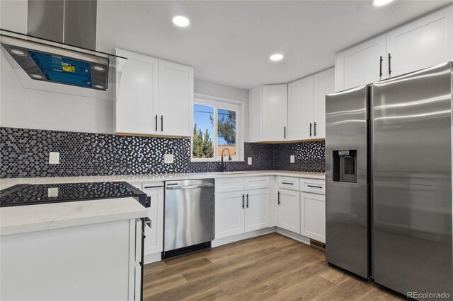 kitchen featuring decorative backsplash, wood finished floors, light countertops, white cabinets, and appliances with stainless steel finishes
