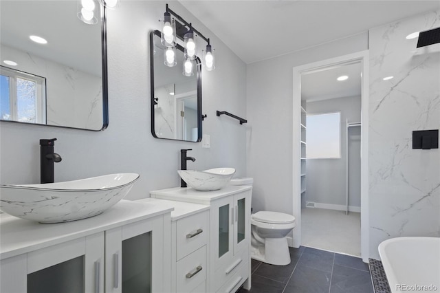 bathroom featuring double vanity, a sink, a freestanding bath, and tile patterned floors