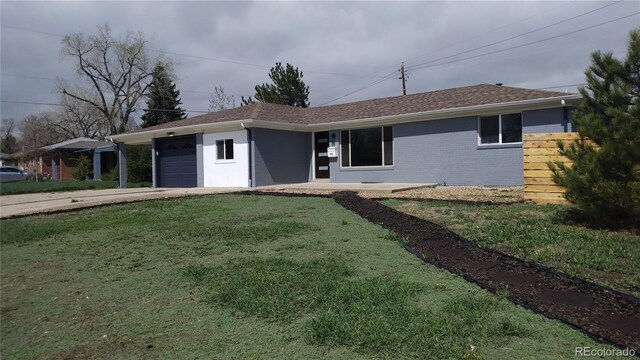 single story home featuring brick siding, driveway, a front yard, and a garage