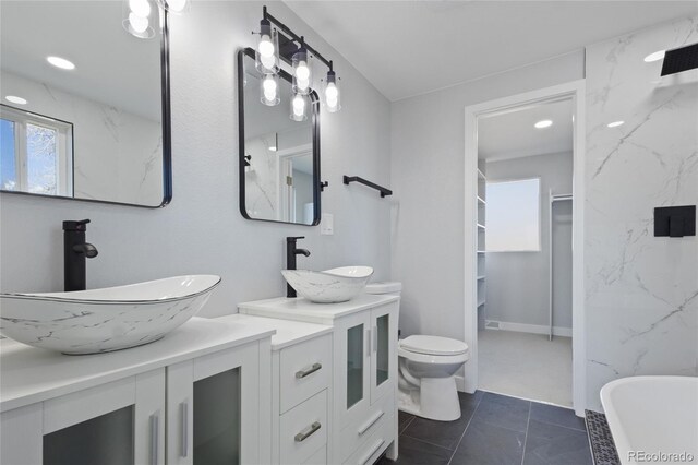 951 E 10th Ave, Broomfield, CO 80020 - full bath featuring double vanity, a freestanding bath, a walk in closet, toilet, and tile patterned floors
