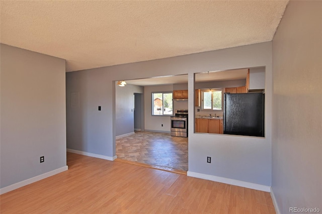 interior space featuring baseboards, a textured ceiling, and light wood finished floors