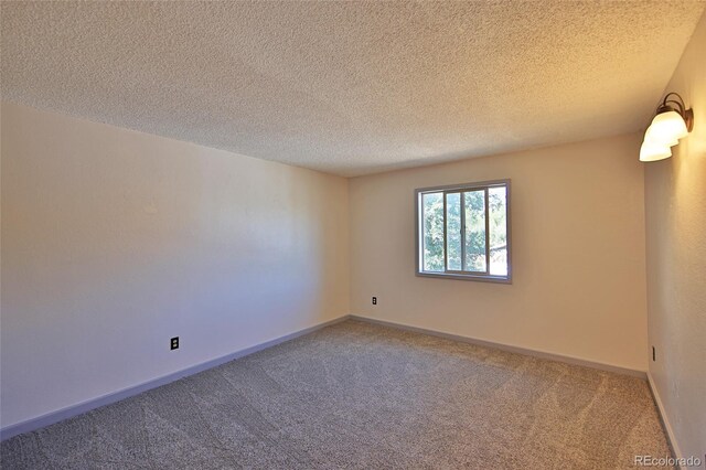 spare room featuring carpet, baseboards, and a textured ceiling