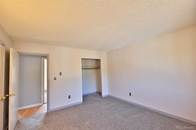 unfurnished bedroom with a closet, light colored carpet, a textured ceiling, and baseboards