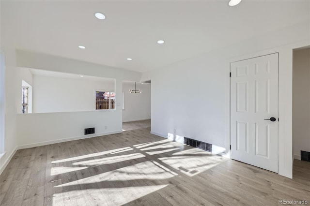 spare room with light hardwood / wood-style floors and a chandelier