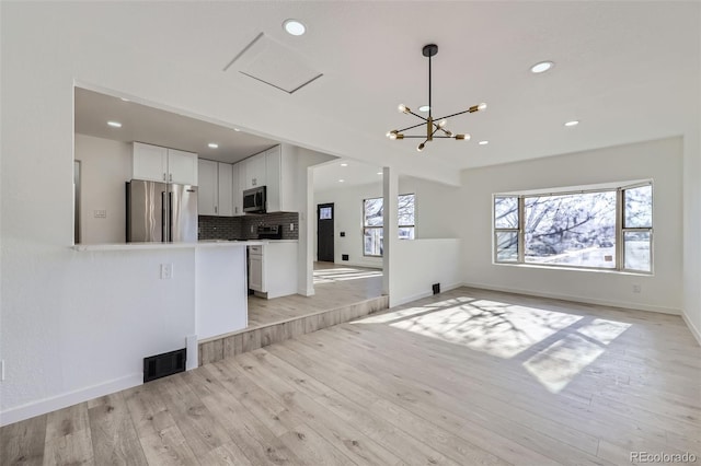 unfurnished living room with a chandelier and light hardwood / wood-style flooring