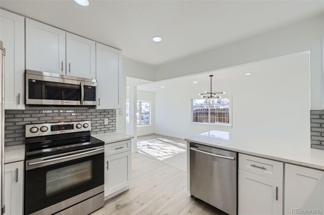 kitchen featuring backsplash, white cabinets, a chandelier, and appliances with stainless steel finishes