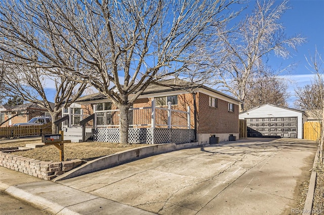 view of front facade featuring a detached garage, fence, a wooden deck, an outdoor structure, and brick siding