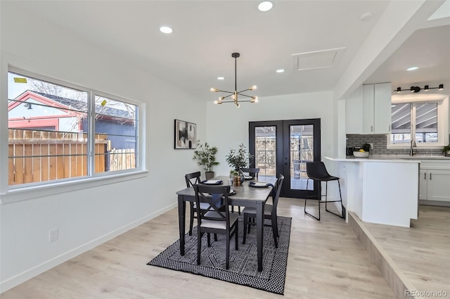 dining space with light wood-type flooring, a healthy amount of sunlight, recessed lighting, and french doors