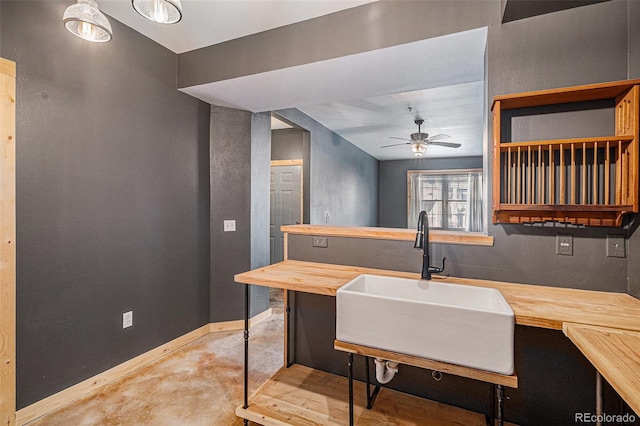 kitchen featuring ceiling fan, wood counters, and sink