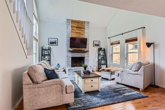living area featuring baseboards, wood finished floors, lofted ceiling, and a fireplace